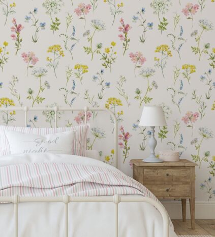 A cozy bedroom with floral wallpaper, a white bed with striped bedding, and a wooden bedside table with a lamp.