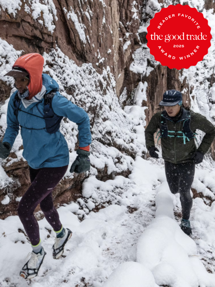 Two people trail running through a snowy canyon, wearing winter sports gear. A "Reader Favorite" and "The Good Trade Award Winner 2025" badge is visible.