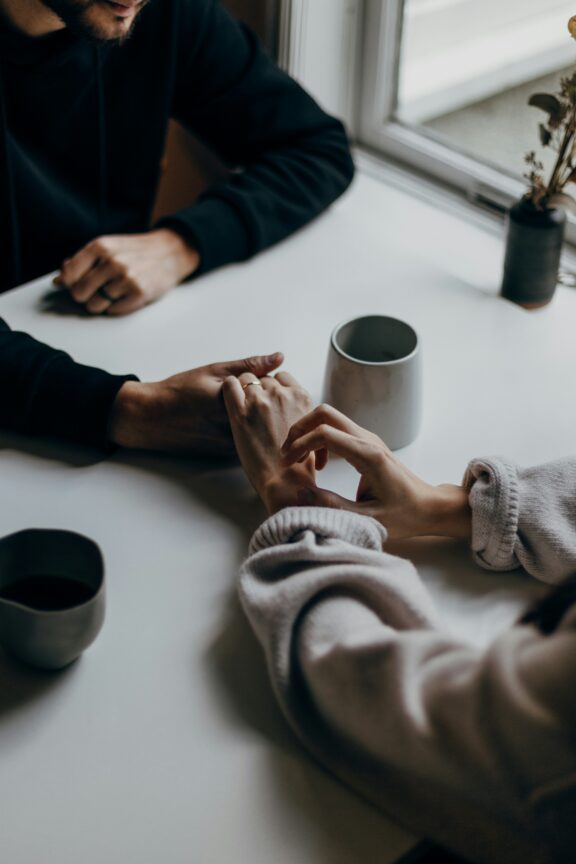 A man and woman holding hands at a table.