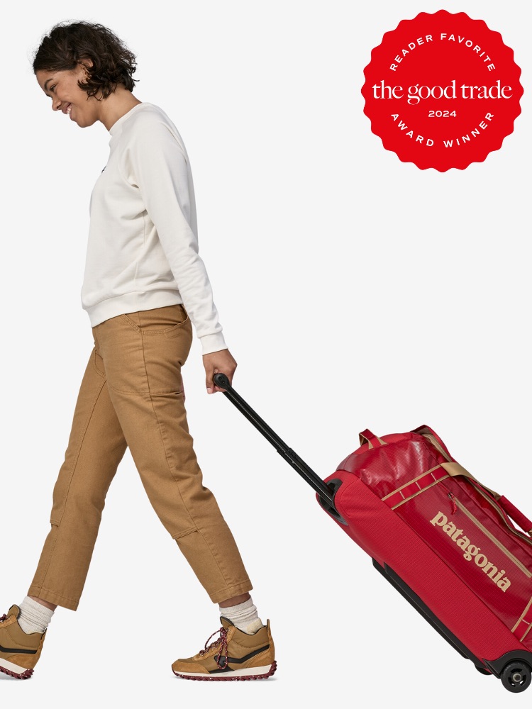 Woman in casual attire walking and pulling a red patagonia wheeled suitcase, with a "reader favorite 2024" badge on top right.