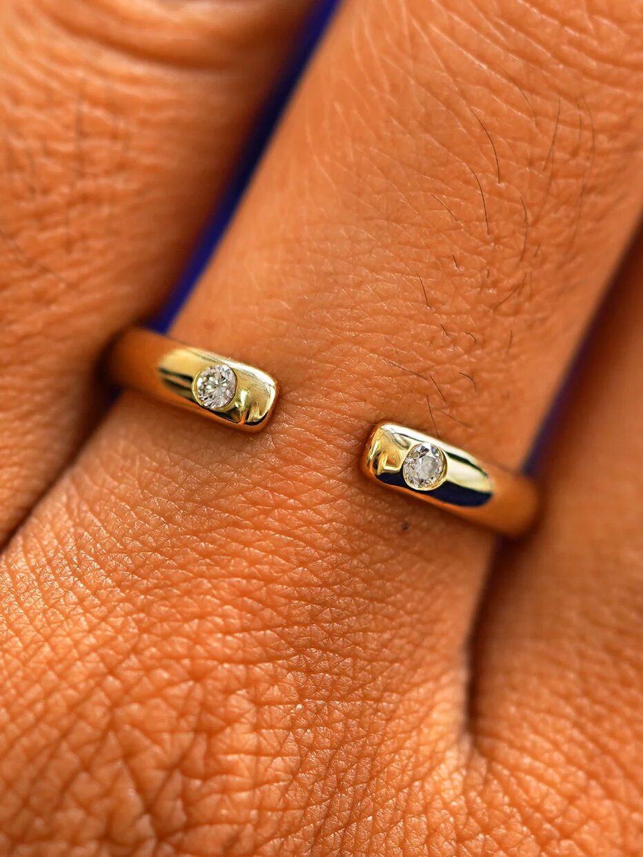 Close-up view of two gold rings, each adorned with a small diamond, worn on adjacent fingers.