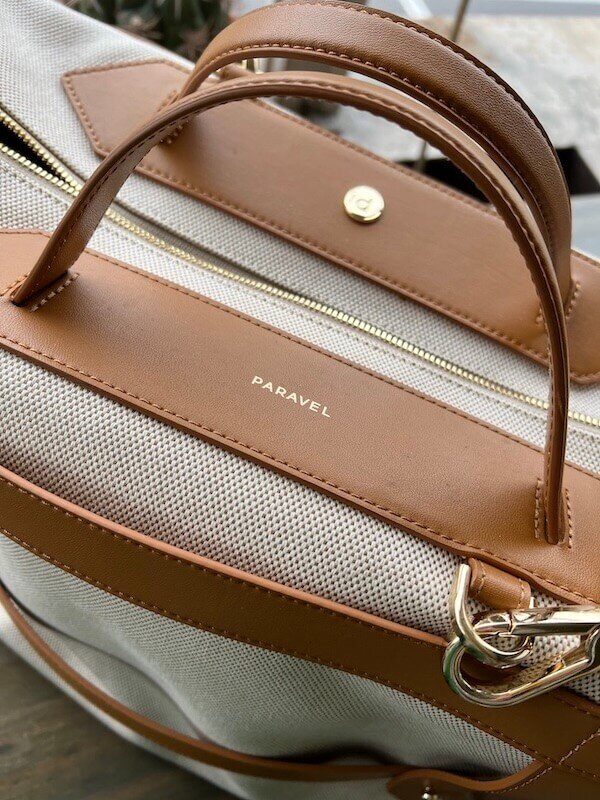 Close-up of a paravel brand bag featuring tan leather accents, metal hardware, and textured fabric.