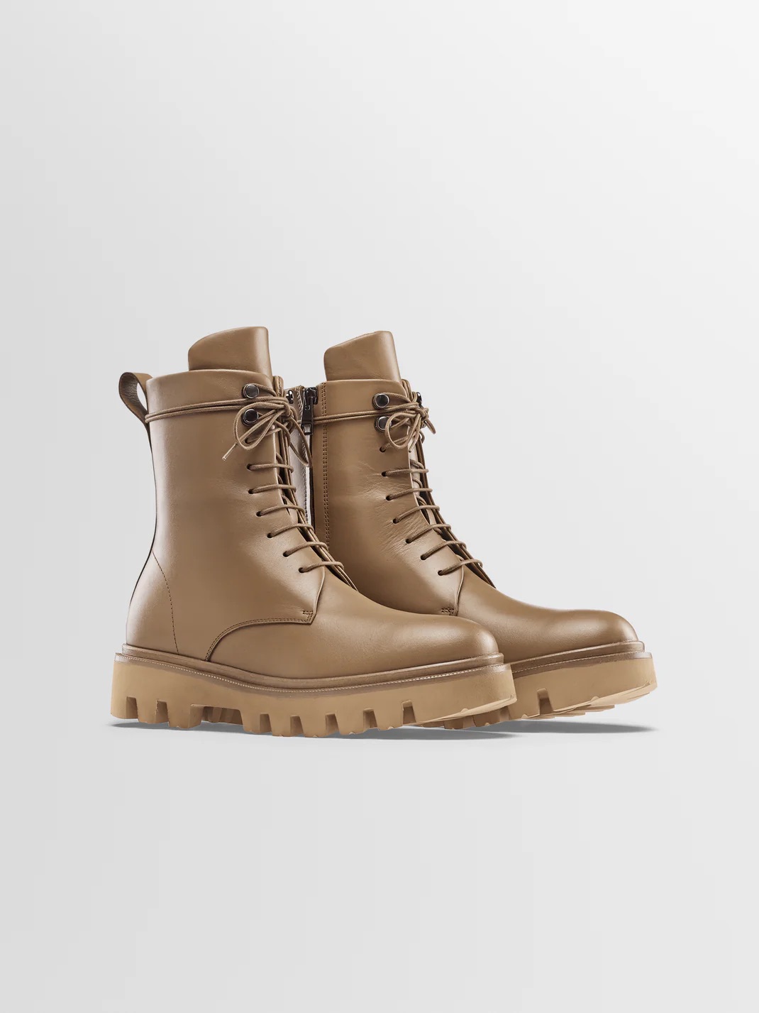 A pair of tan leather lace-up boots with chunky treaded soles against a plain white background.