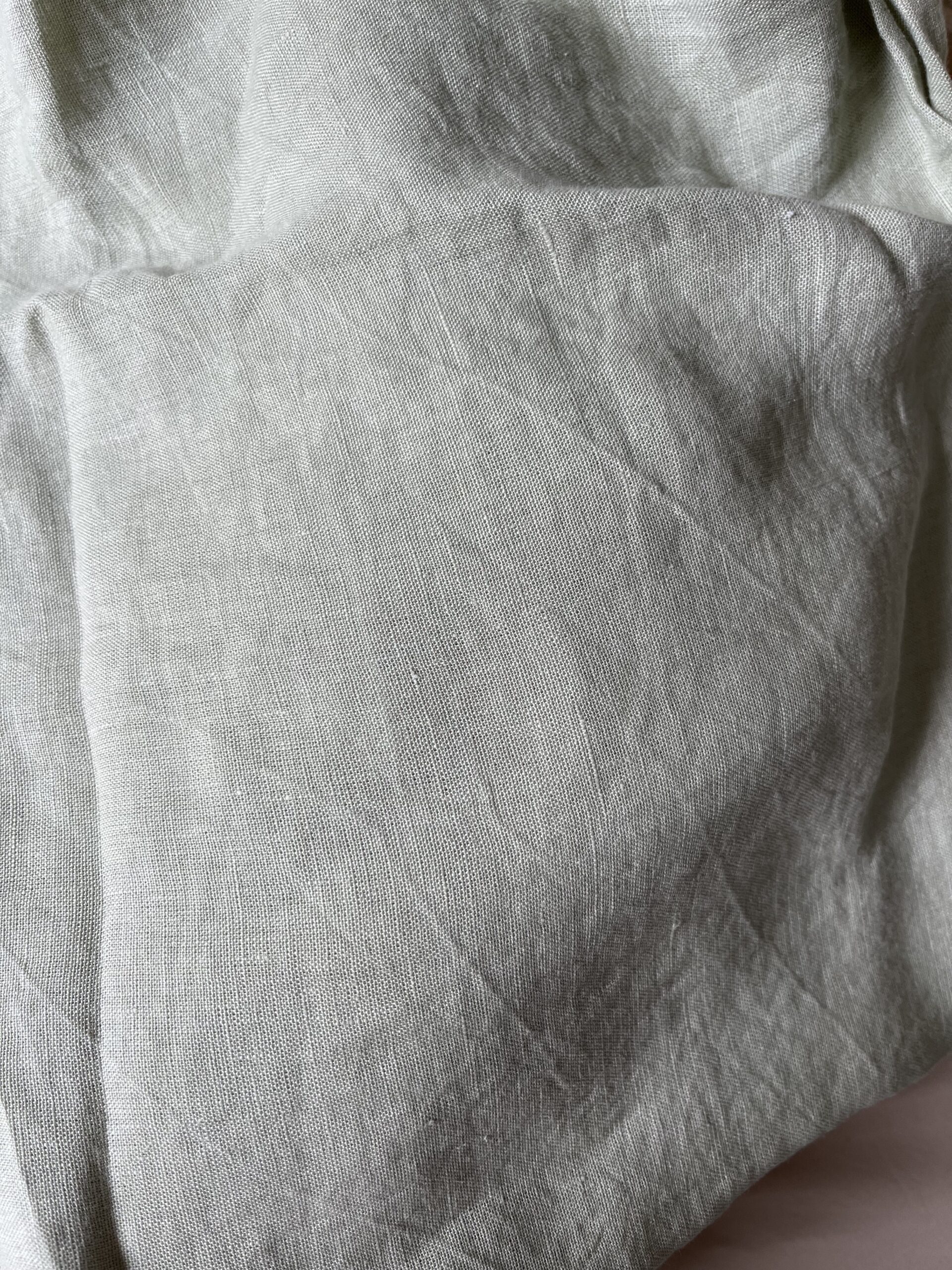 Close-up of a crumpled piece of light gray fabric with visible texture and fine wrinkles.