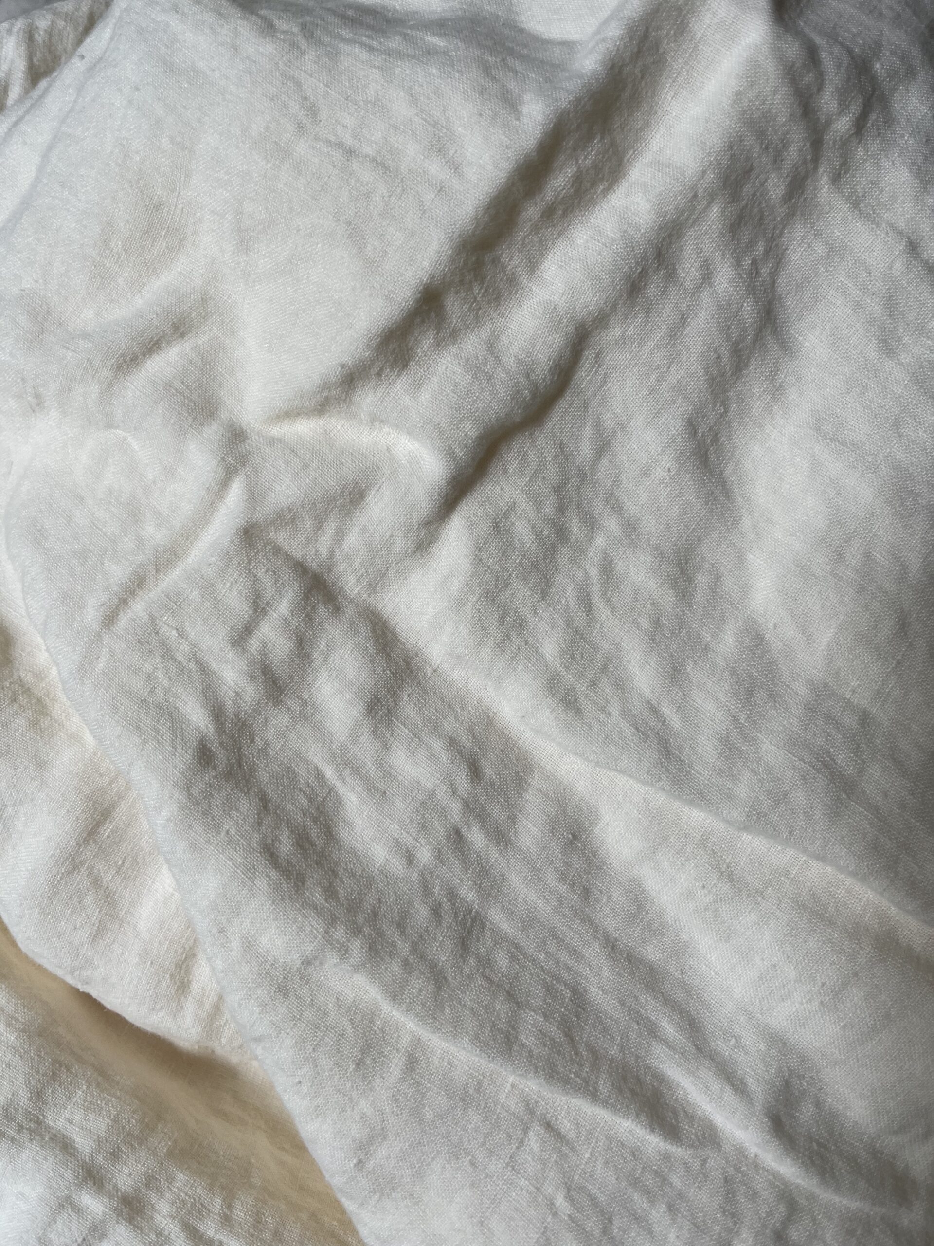 Close-up view of a crumpled, off-white fabric with a slightly textured surface.