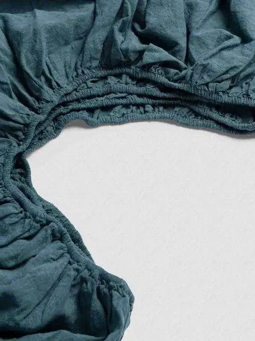 A close-up view of a teal-colored, gathered elastic fabric with a ruched texture.