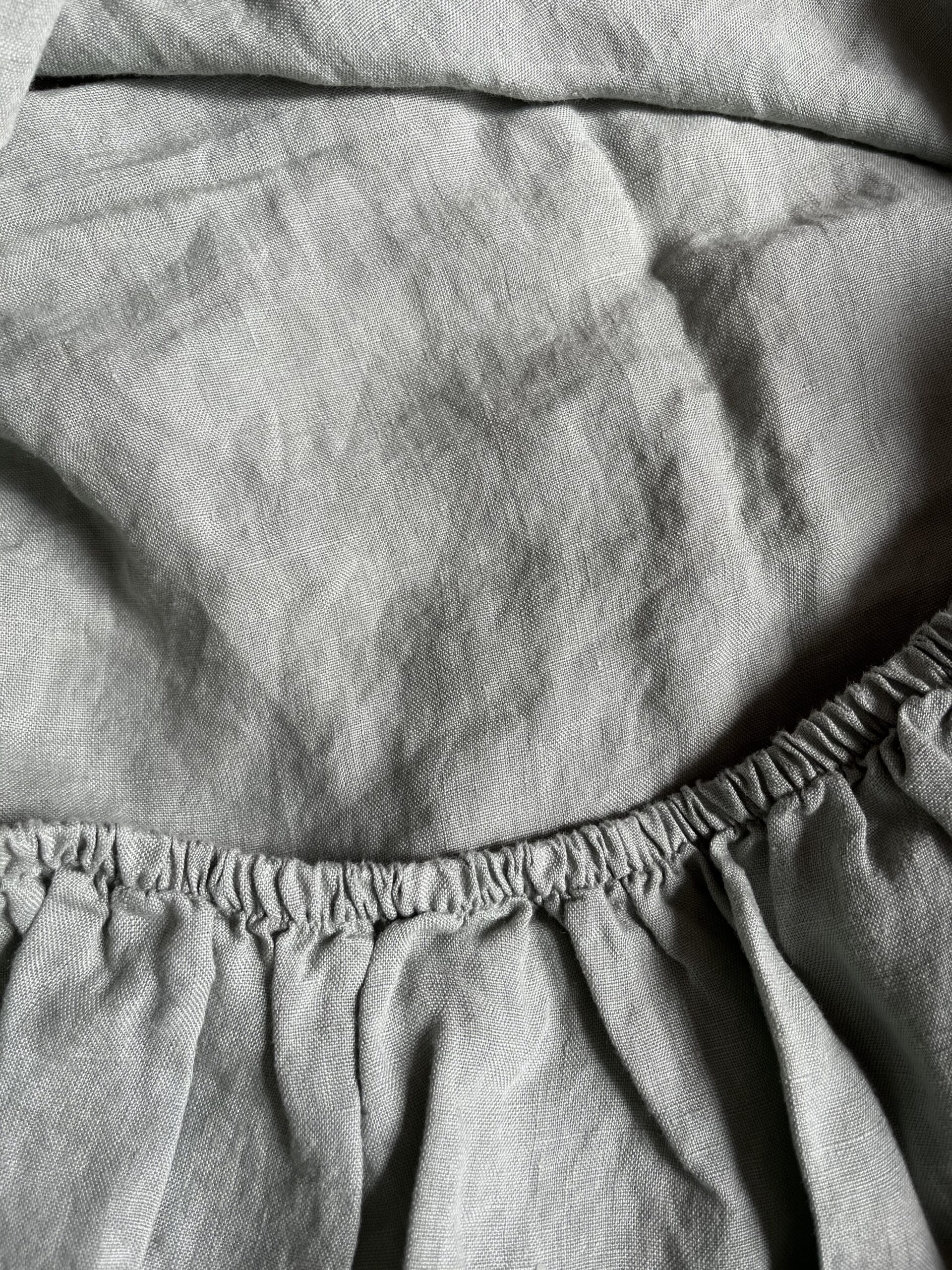Close-up image of a light grey, crumpled fabric with an elastic waistband.