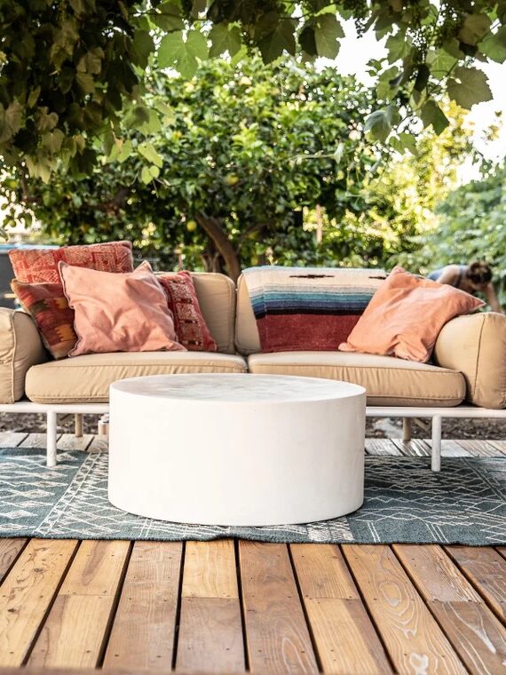 A round stone outdoor table in a backyard patio setting. 