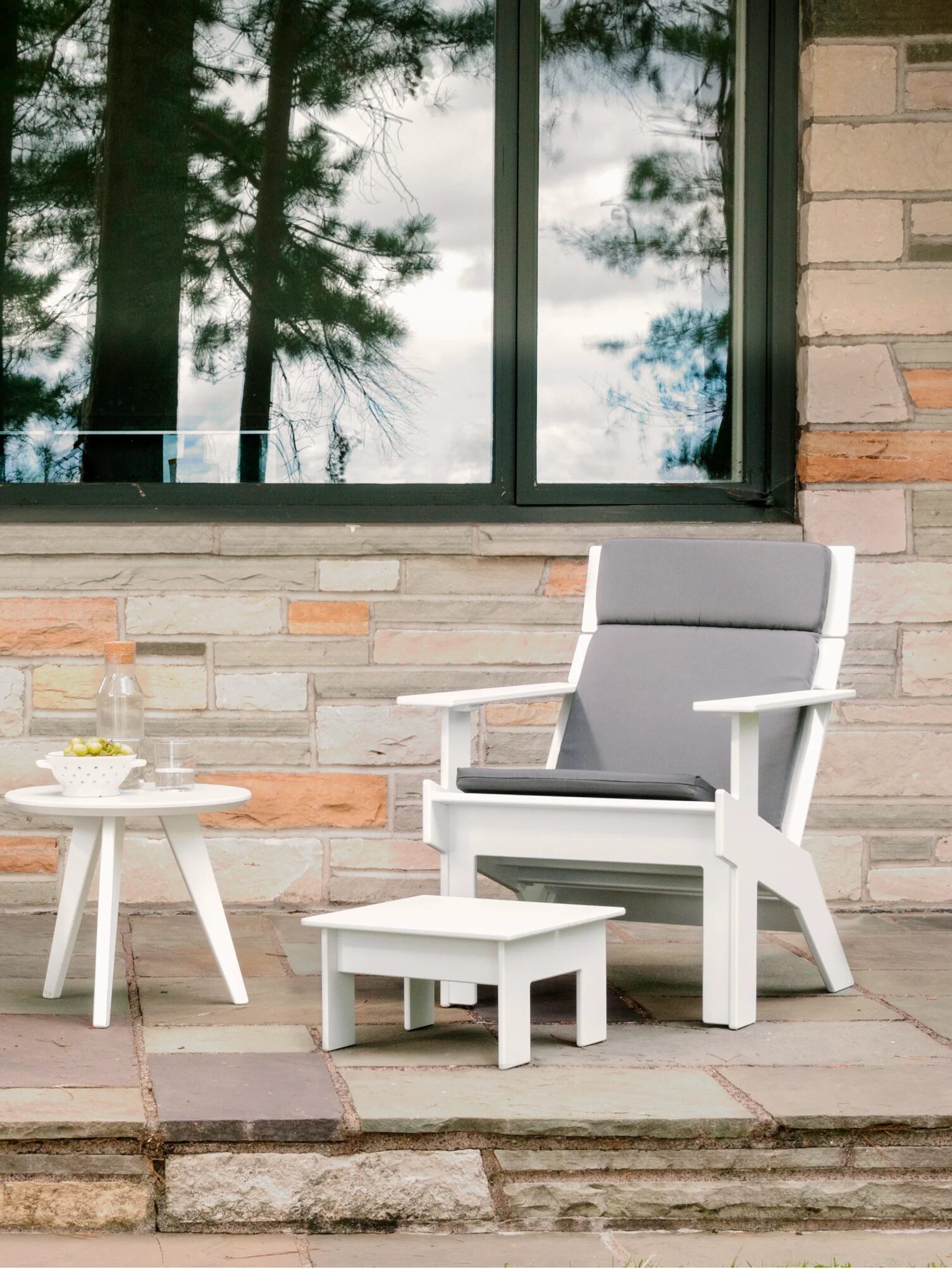 A grey lounge chair and white side table from Loll Designs in an outdoor patio setting.