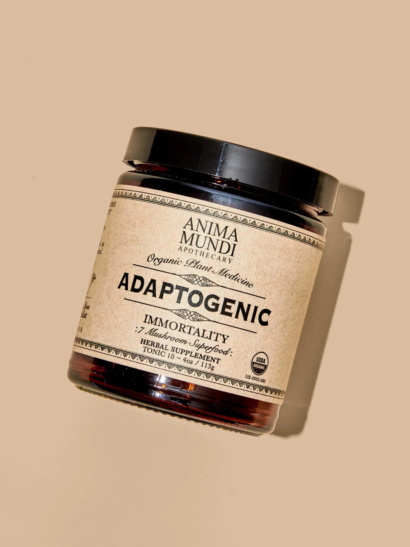 A jar labeled "Anima Mundi Apothecary Adaptogenic Immortality" sits against a beige background. It contains a mushroom and herbal syrup supplement designed to support vitality.