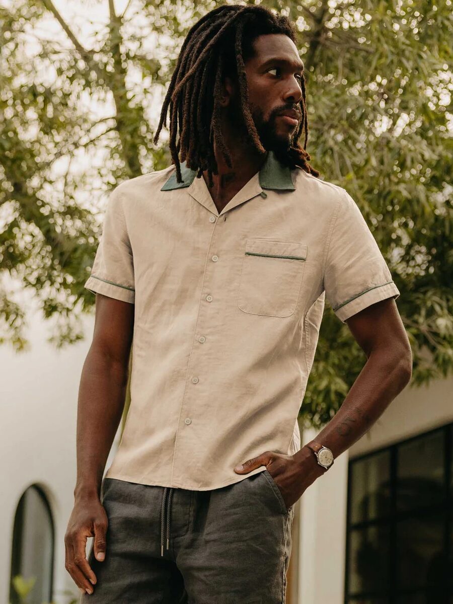 A model wearing a beige and green button down collared shirt and green khaki pants from Taylor Sttich. 