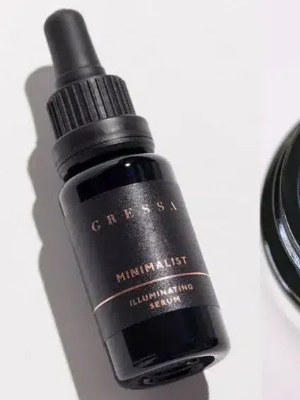 Image shows a bottle of Gressa Minimalist Illuminating Serum, a container of a cream-like cosmetic product, and a close-up of a dropper with liquid product.