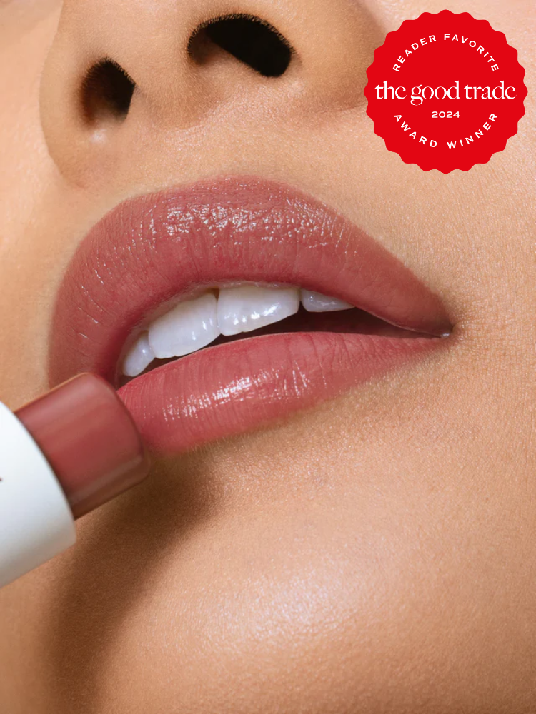 Close-up of a person applying light pink lipstick, with a "Reader Favorite the good trade 2024 Award Winner" badge in the top right corner.