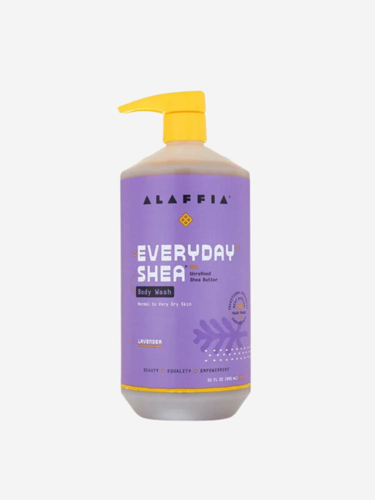 A bottle of Alaffia Everyday Shea Body Wash with a lavender scent. It has a yellow pump top and is labeled for normal to very dry skin.