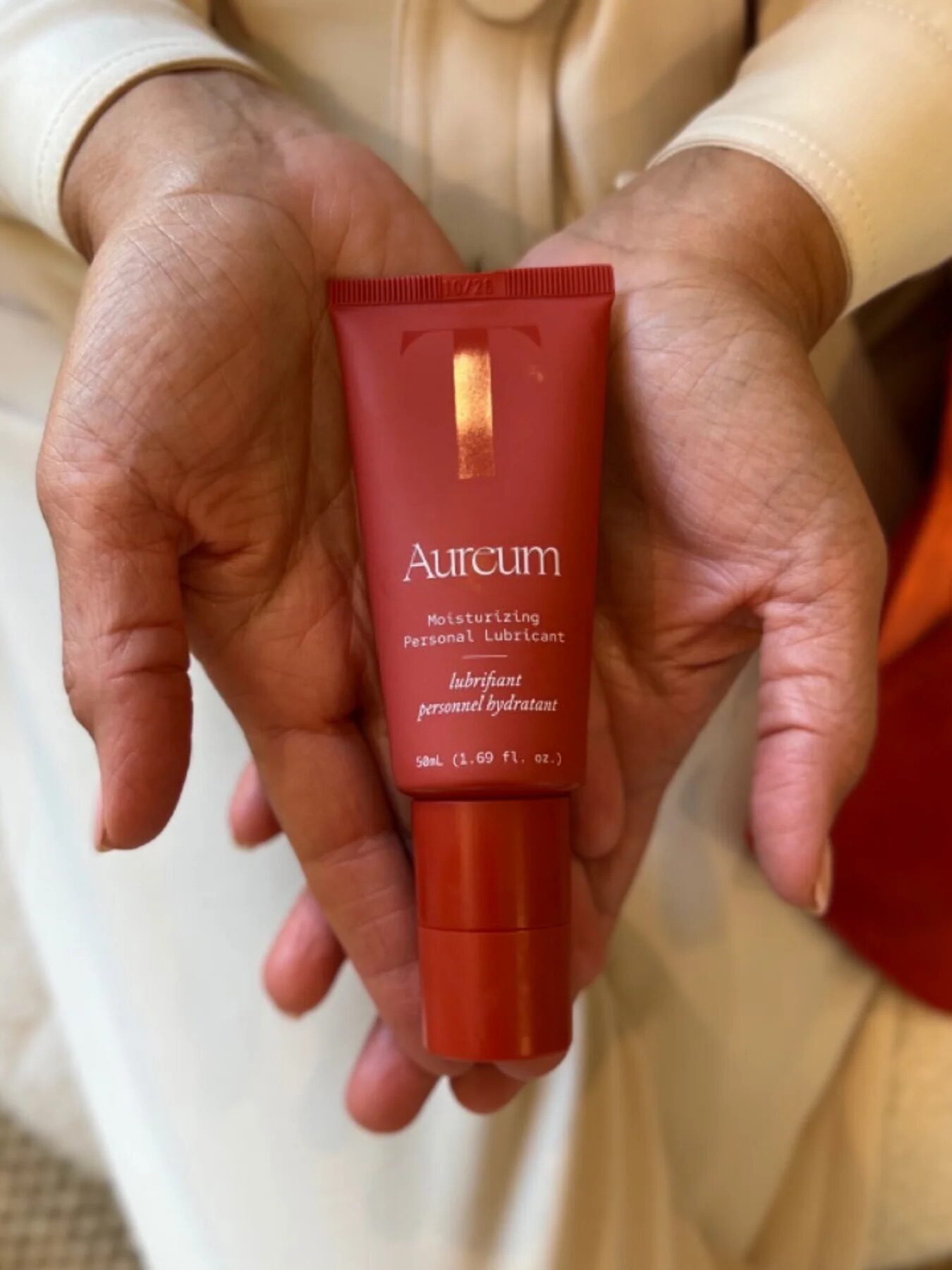 Close-up of a person holding a tube of Aureum Moisturizing Personal Lubricant in their hands, displaying the product label clearly.