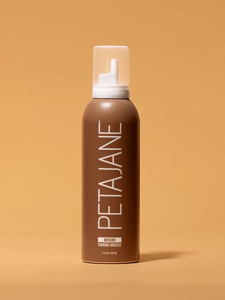 A brown can of PETAJANE Medium Tanning Mousse with a white cap is displayed against a warm beige background.