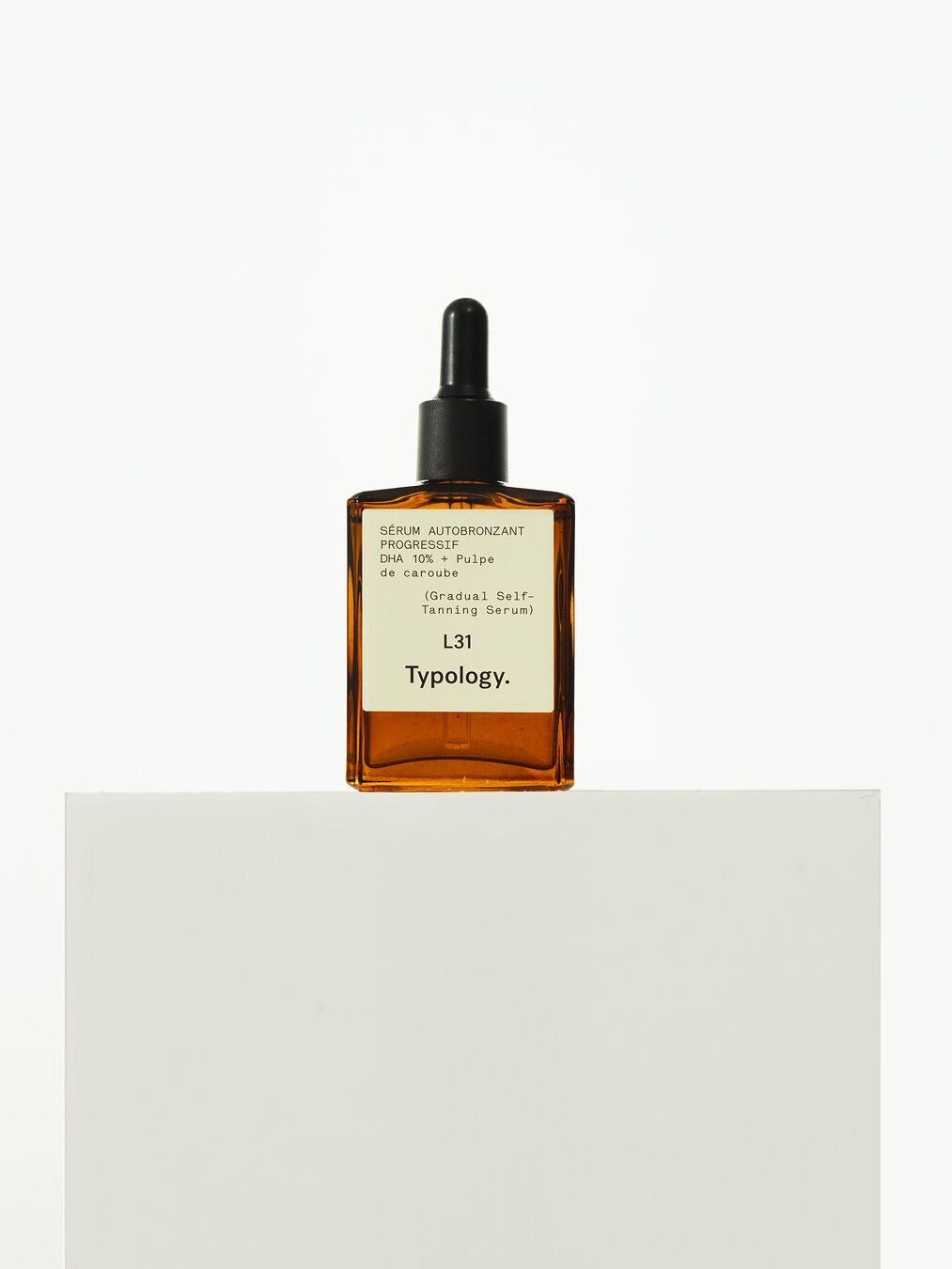 A bottle of Typology Lait Self-Tanning Serum is placed on a white surface against a plain white background.