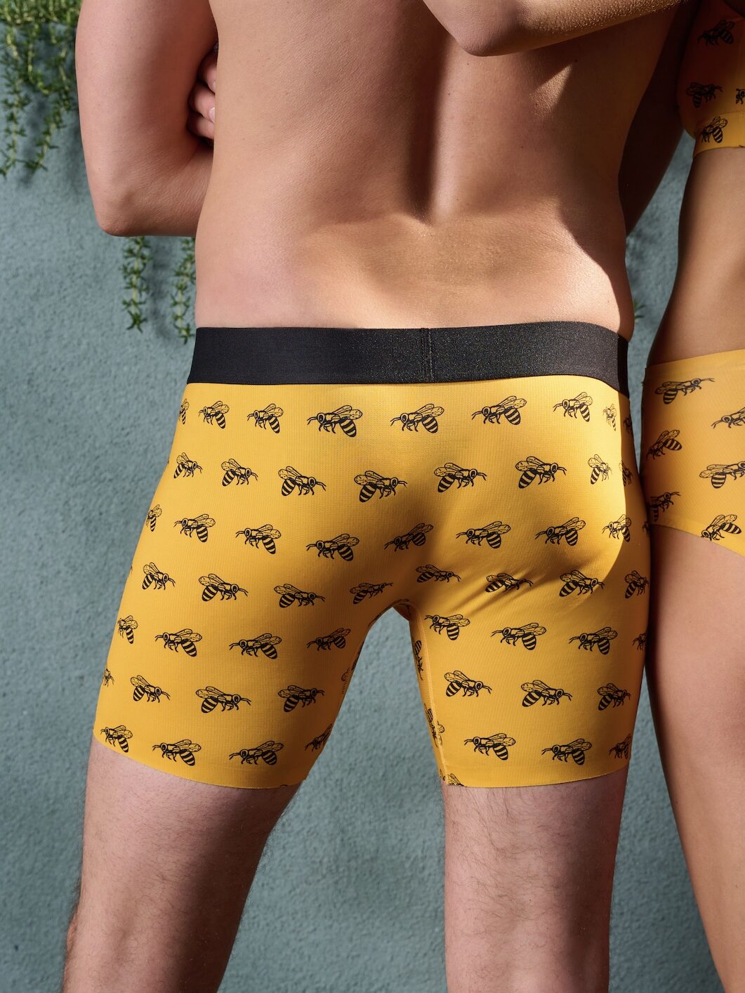 A model wearing a pair of yellow boxer shorts with a bee print on them from Meundies. 