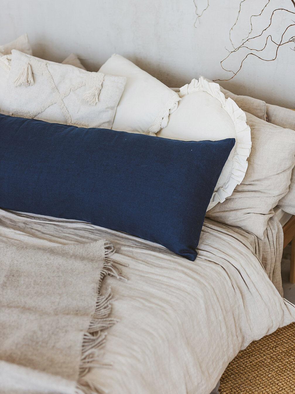 A long blue lumbar pillow from Mini Camp on a bed.