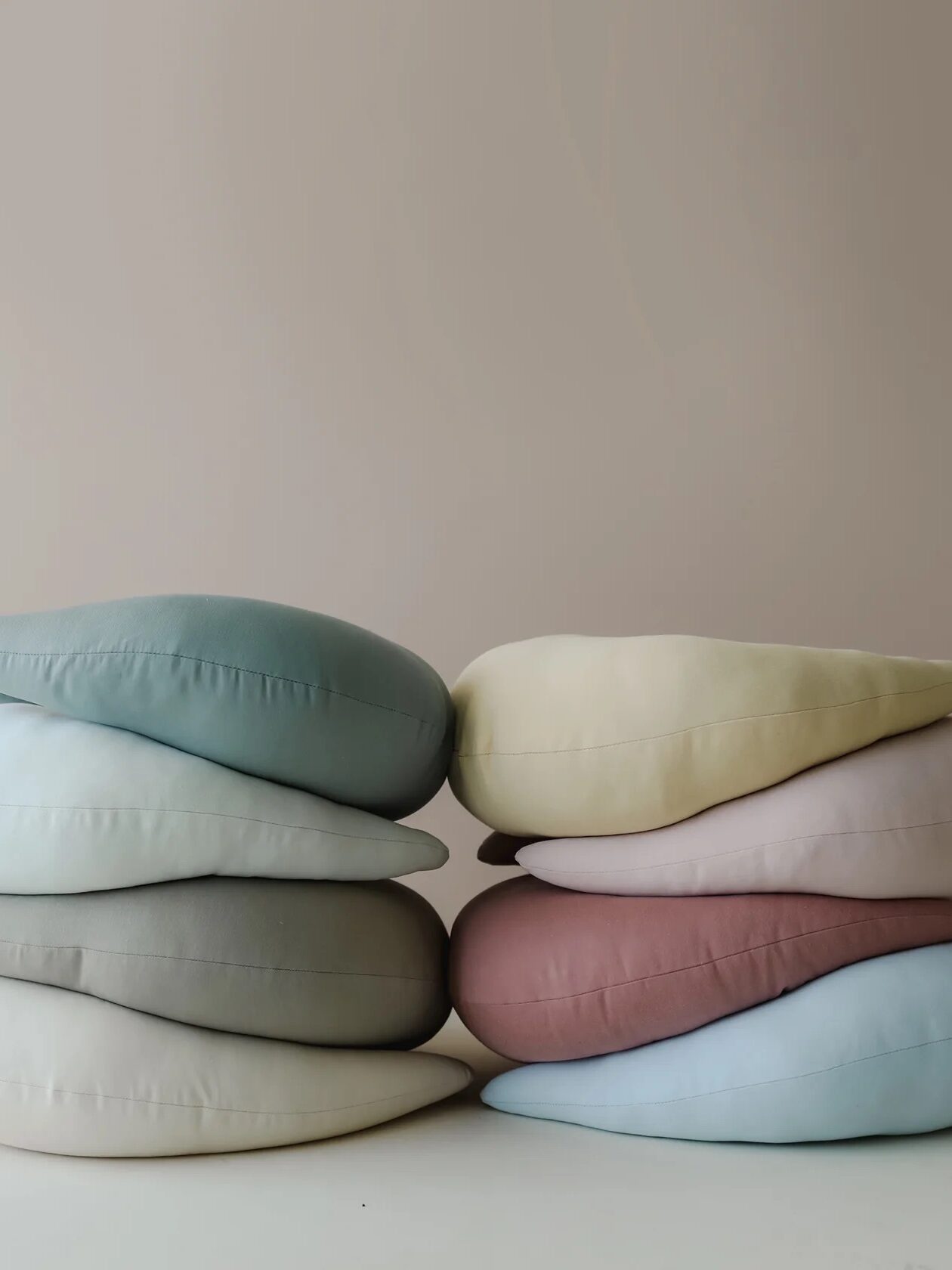 Two stacks of colorful Snuggle Me Organic pregnancy pillows.