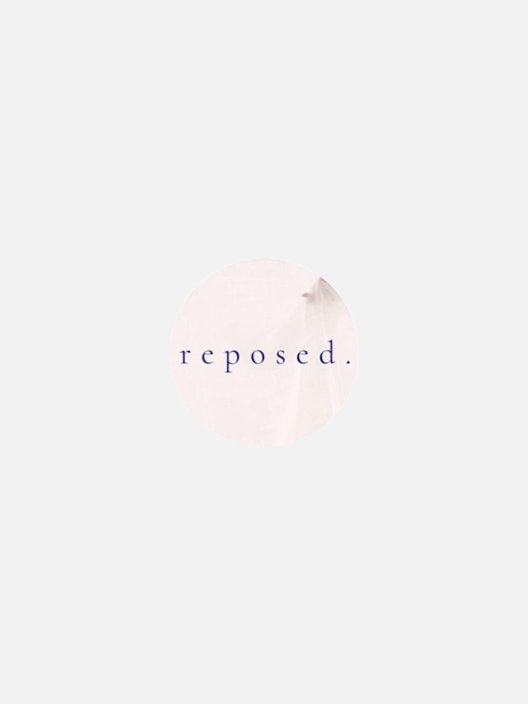 A light gray circular logo with the word "reposed." written in lowercase purple letters in the center.