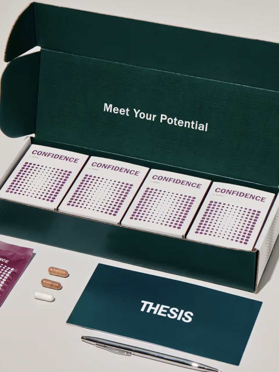 An open green box with the text "Meet Your Potential" on the lid contains four "Confidence" supplement boxes, a "THESIS" card, a pen, and two supplementary pills beside a packet labeled "Confidence.