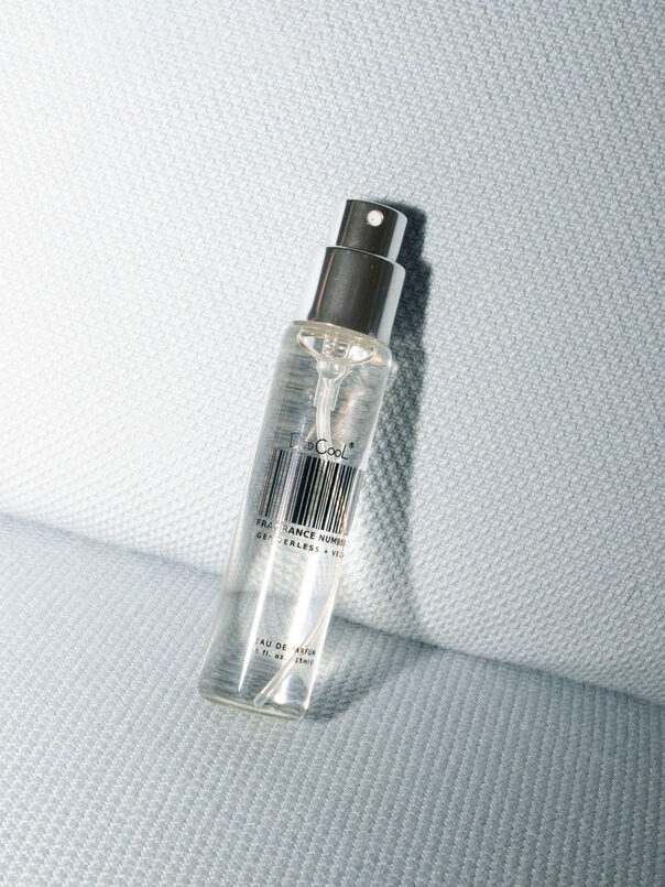 A spray bottle of Les Couleurs Humaines fragrance rests on a grey textured surface.