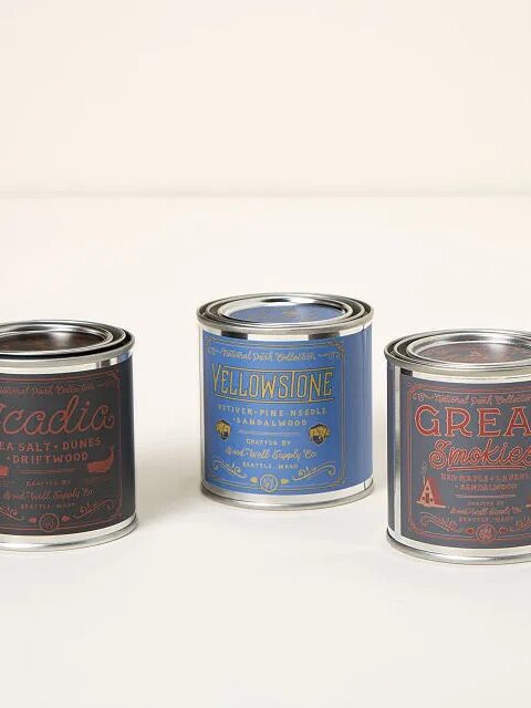 Three labeled metal tins of soy candles in different scents: Acadia, Yellowstone, and Great Smokies, are placed on a neutral background.