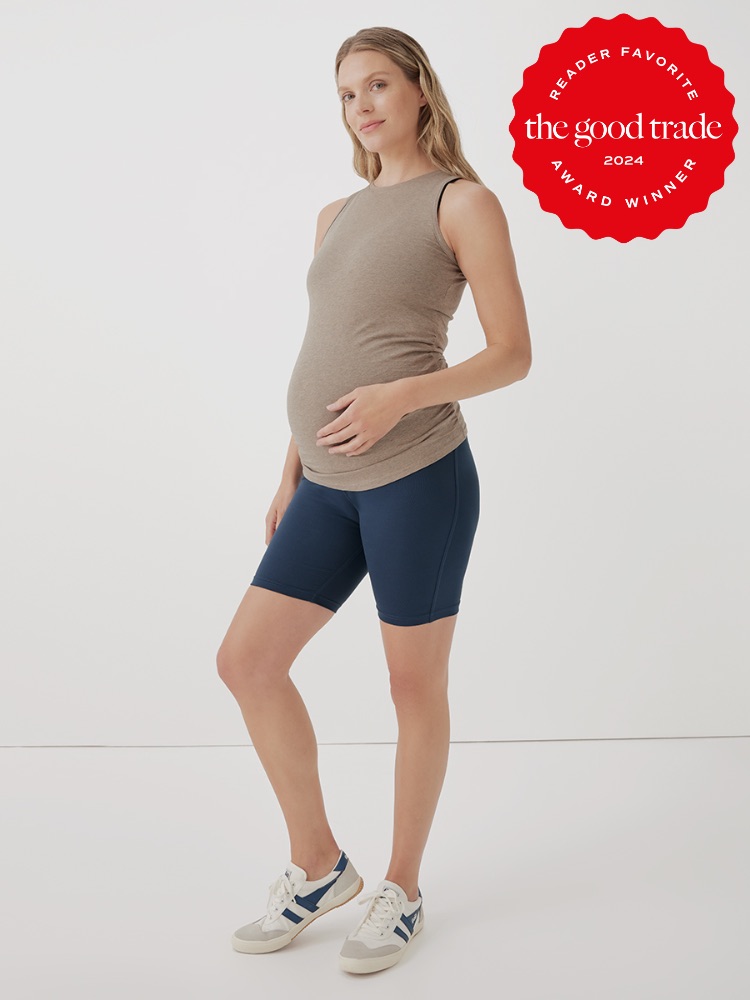 A pregnant woman wearing a tan sleeveless top, navy blue shorts, and white sneakers stands against a plain white background. A red badge in the corner reads, "Reader Favorite, The Good Trade, 2024 Award Winner.