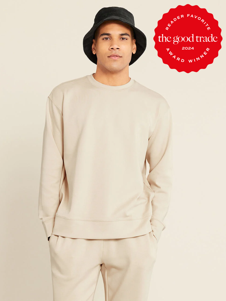 A person wearing a beige sweatshirt and matching sweatpants with a black bucket hat stands against a plain background. A red badge in the corner reads "Reader Favorite - The Good Trade Award Winner 2024.