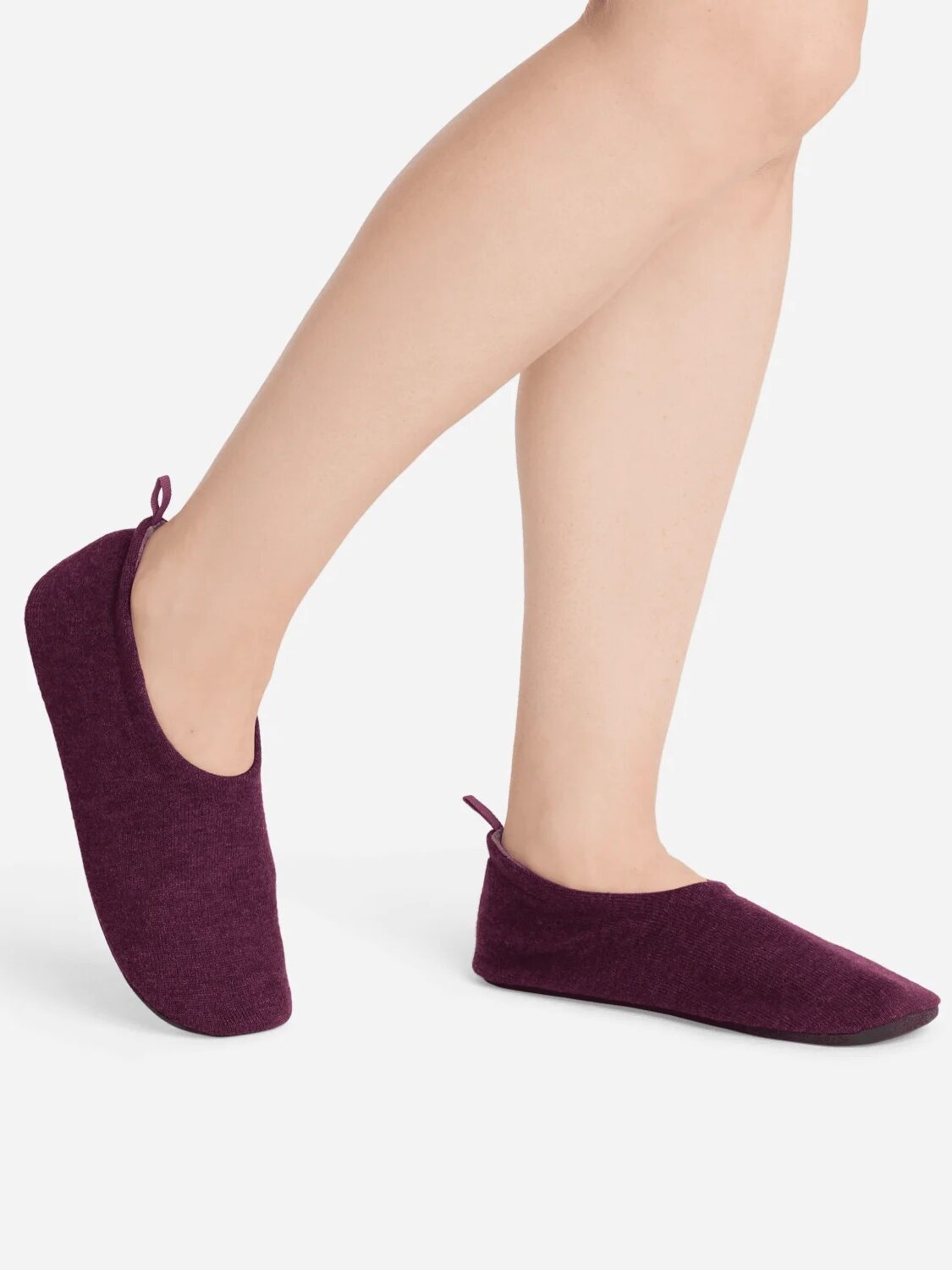 A person wearing burgundy slipper socks against a white background.