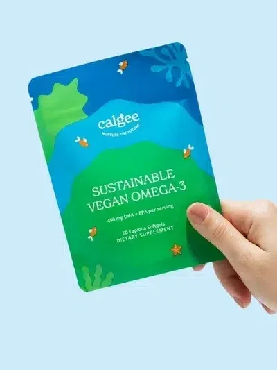 A hand holding a packet of Calgee Sustainable Vegan Omega-3 dietary supplements against a light blue background.