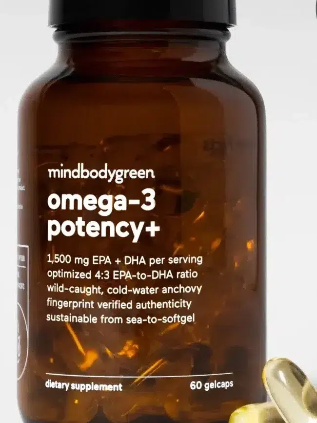 A bottle of mindbodygreen omega-3 potency+ supplements. The label highlights 1,500 mg EPA+DHA per serving with sustainable sourcing. Two softgel capsules are shown next to the bottle. .