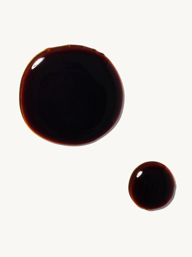 Two circular drops of a dark liquid on a white background.