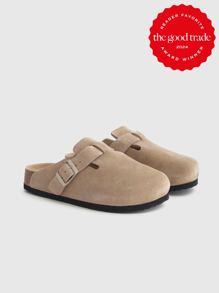 A pair of beige suede slip-on clogs with a buckle strap beside a red badge reading "Reader Favorite The Good Trade 2024 Award Winner.