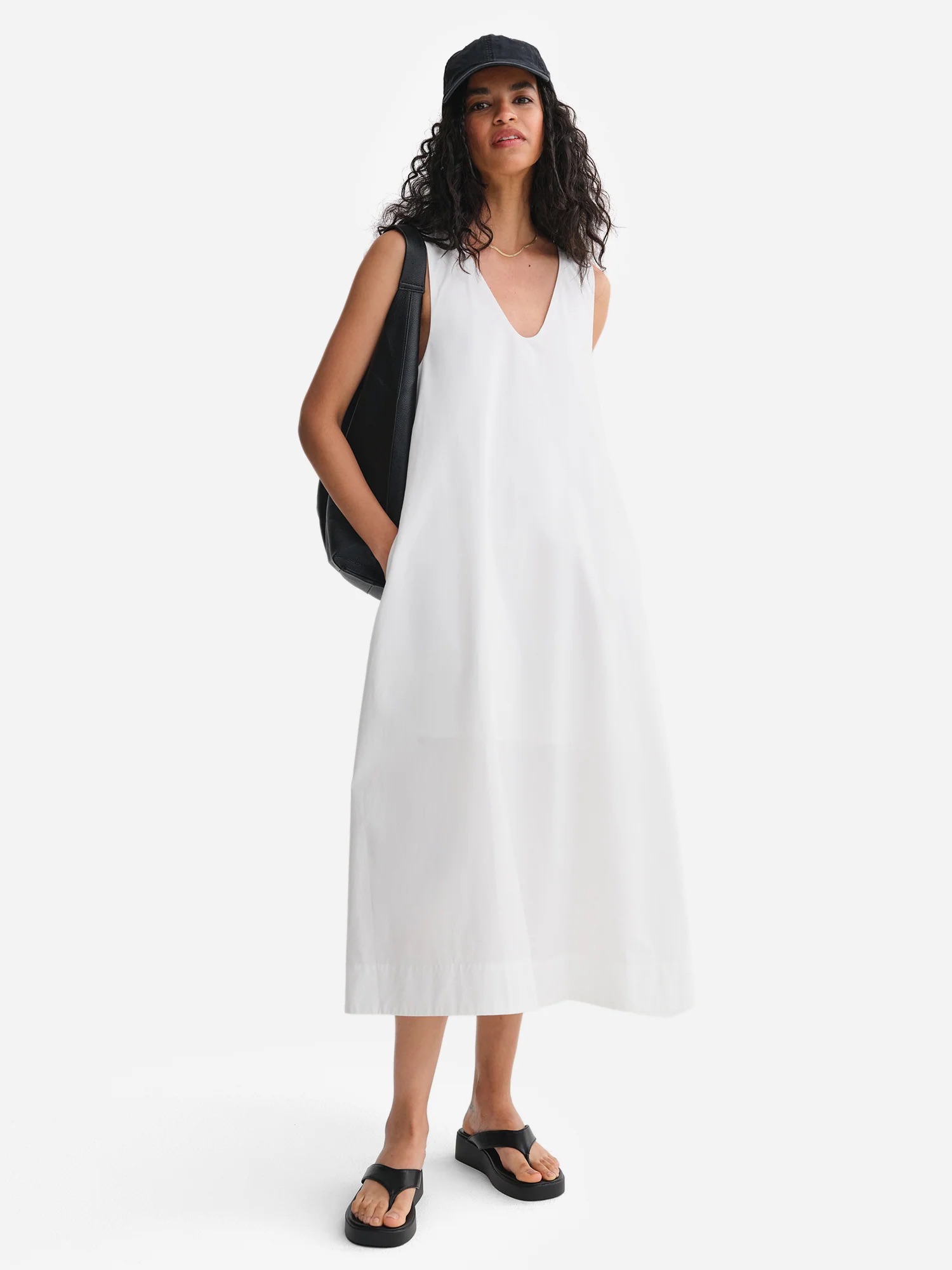 A model wearing a v-neck sleeveless max dress in white from MATE. 