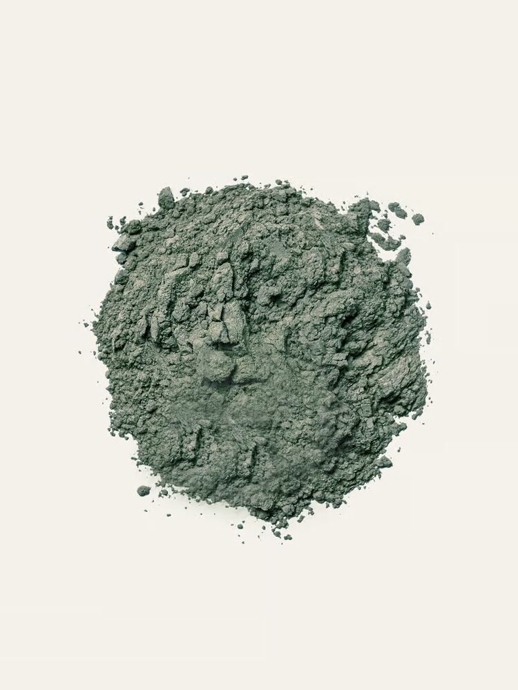 A pile of loose, greenish powder on a plain white background.