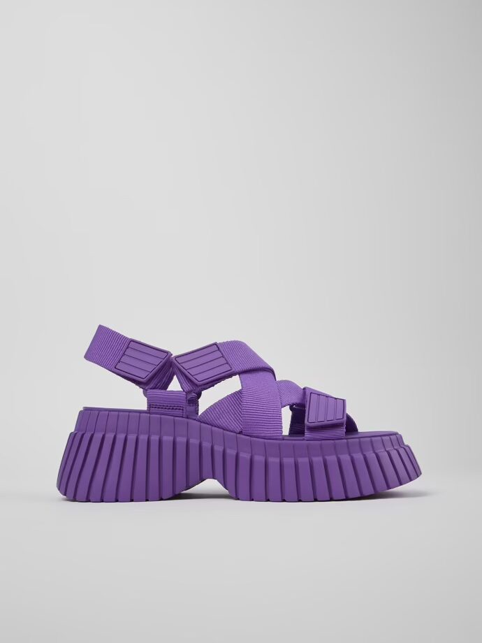 A purple platform sandal with thick, ridged soles, multiple straps, and a closed heel, displayed on a plain white background.