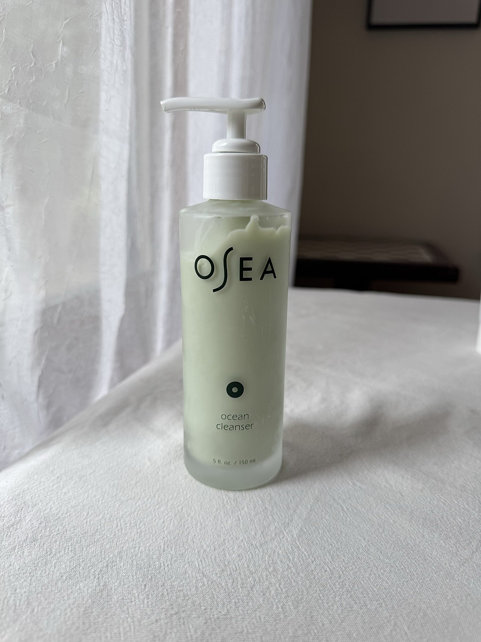 A bottle of OSEA Ocean Cleanser on a white fabric surface. 