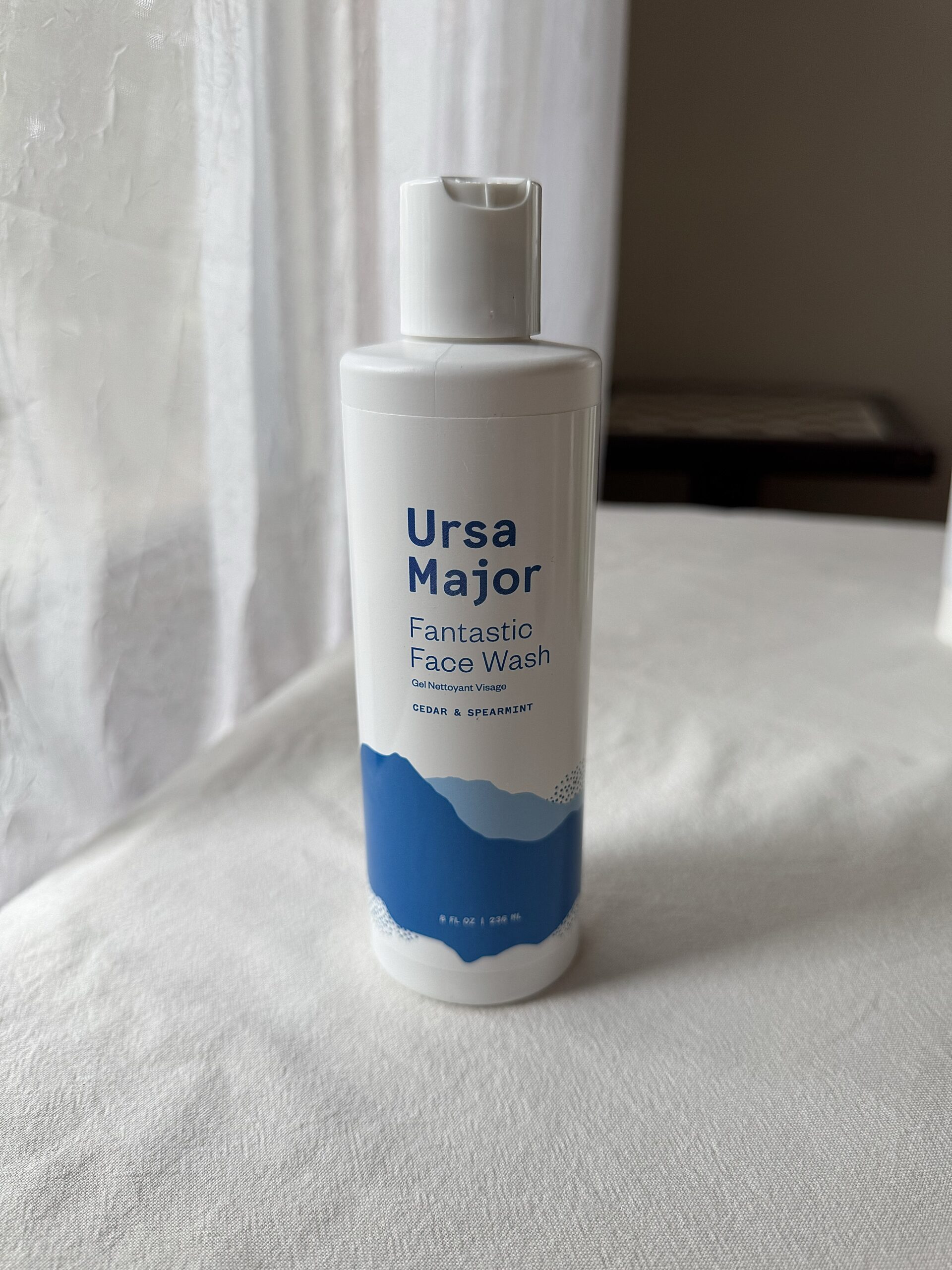 The Ursa Major Fantastic Face Wash bottle on a white fabric surface. 