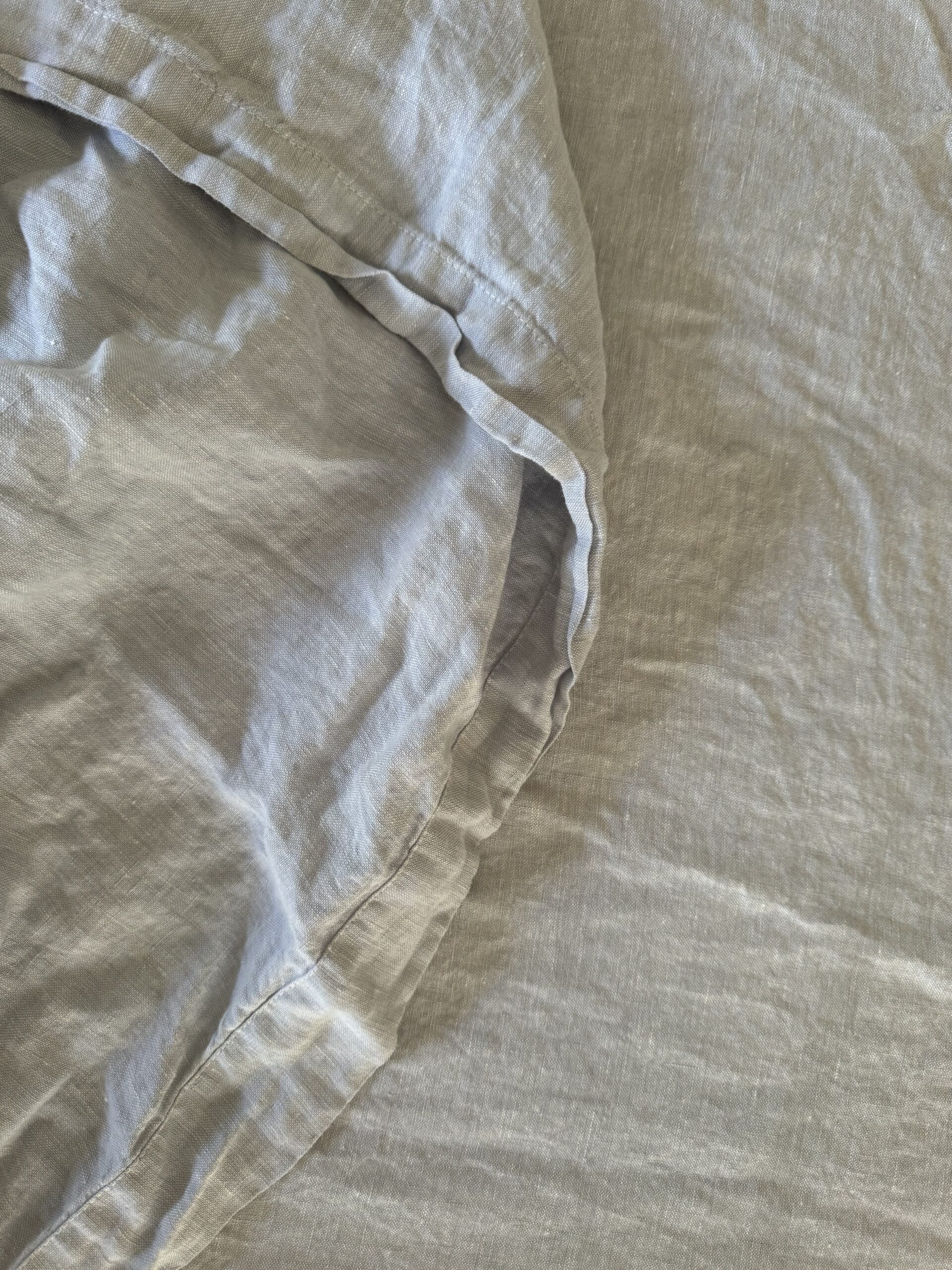 Close-up of a crumpled, light gray bedsheet, showcasing its texture and creases.