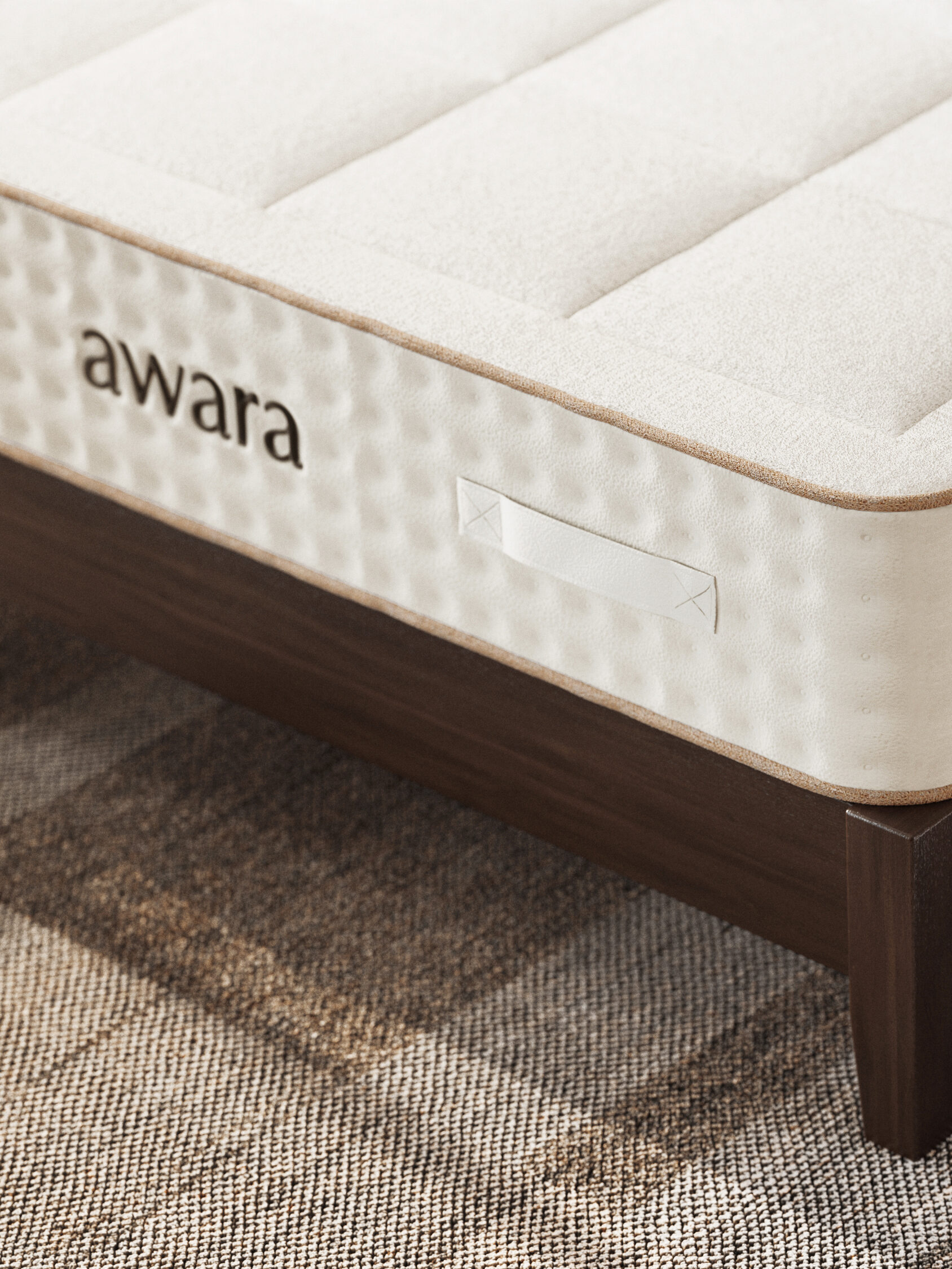 A close-up view of an Awara mattress on a wooden bed frame, showing its textured fabric and side handles.