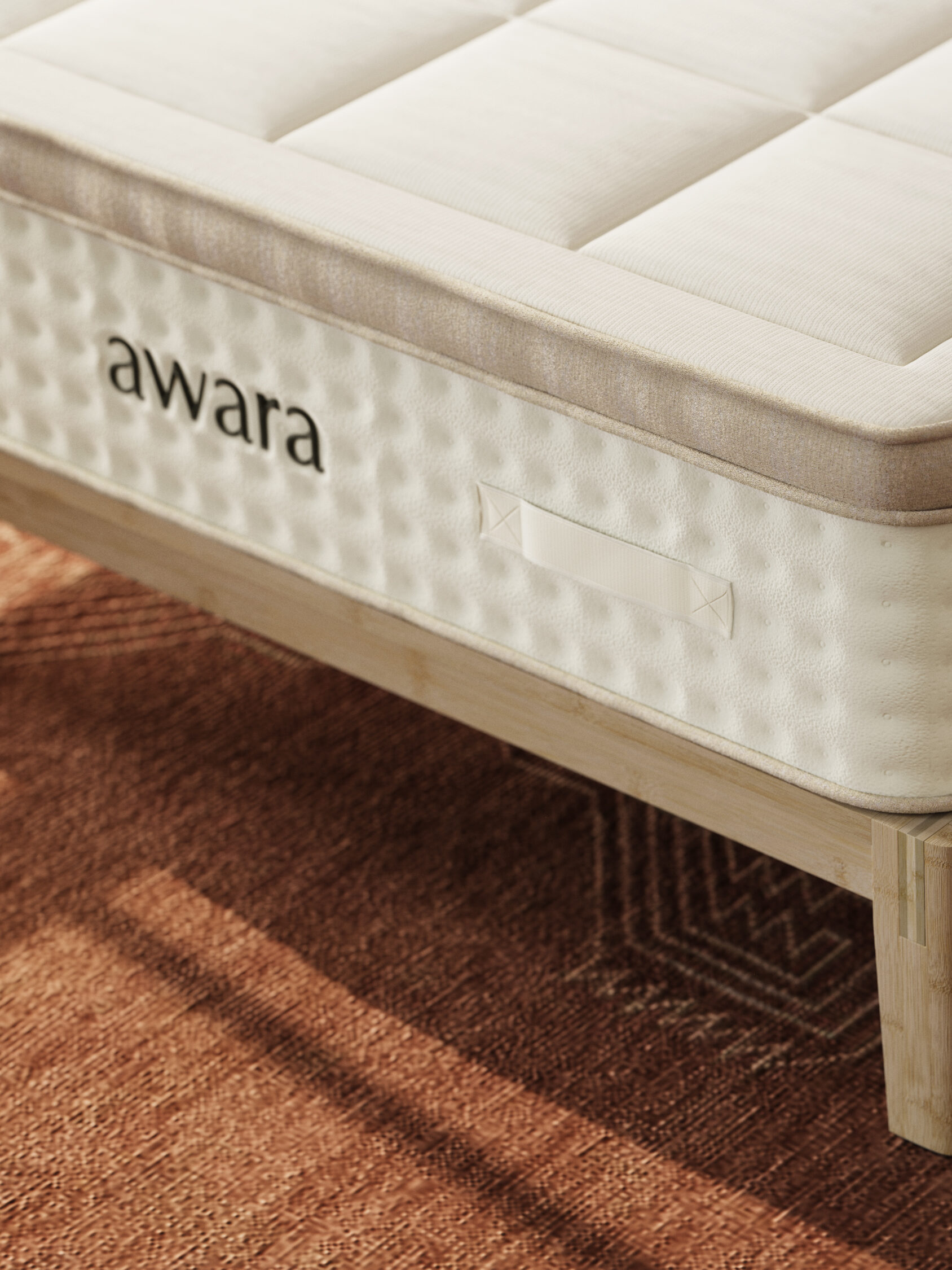 Close-up of a mattress with the brand name "awara" embossed on the side, placed on a wooden bed frame, and resting on a patterned rug.