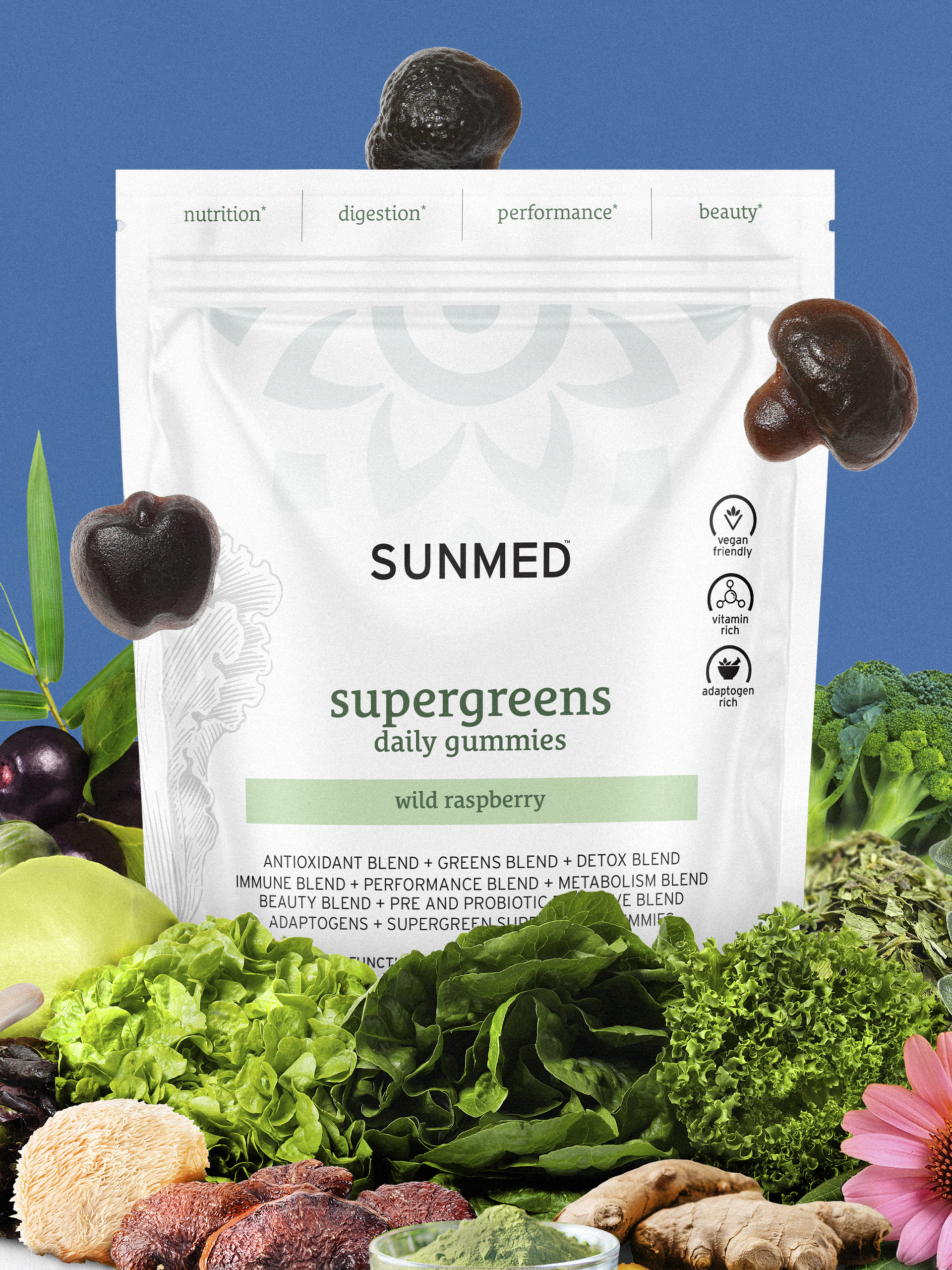 A bag of SunMed Supergreens daily gummies (wild raspberry flavor) surrounded by various green vegetables and fruits. The bag lists benefits like digestion, energy, and performance.