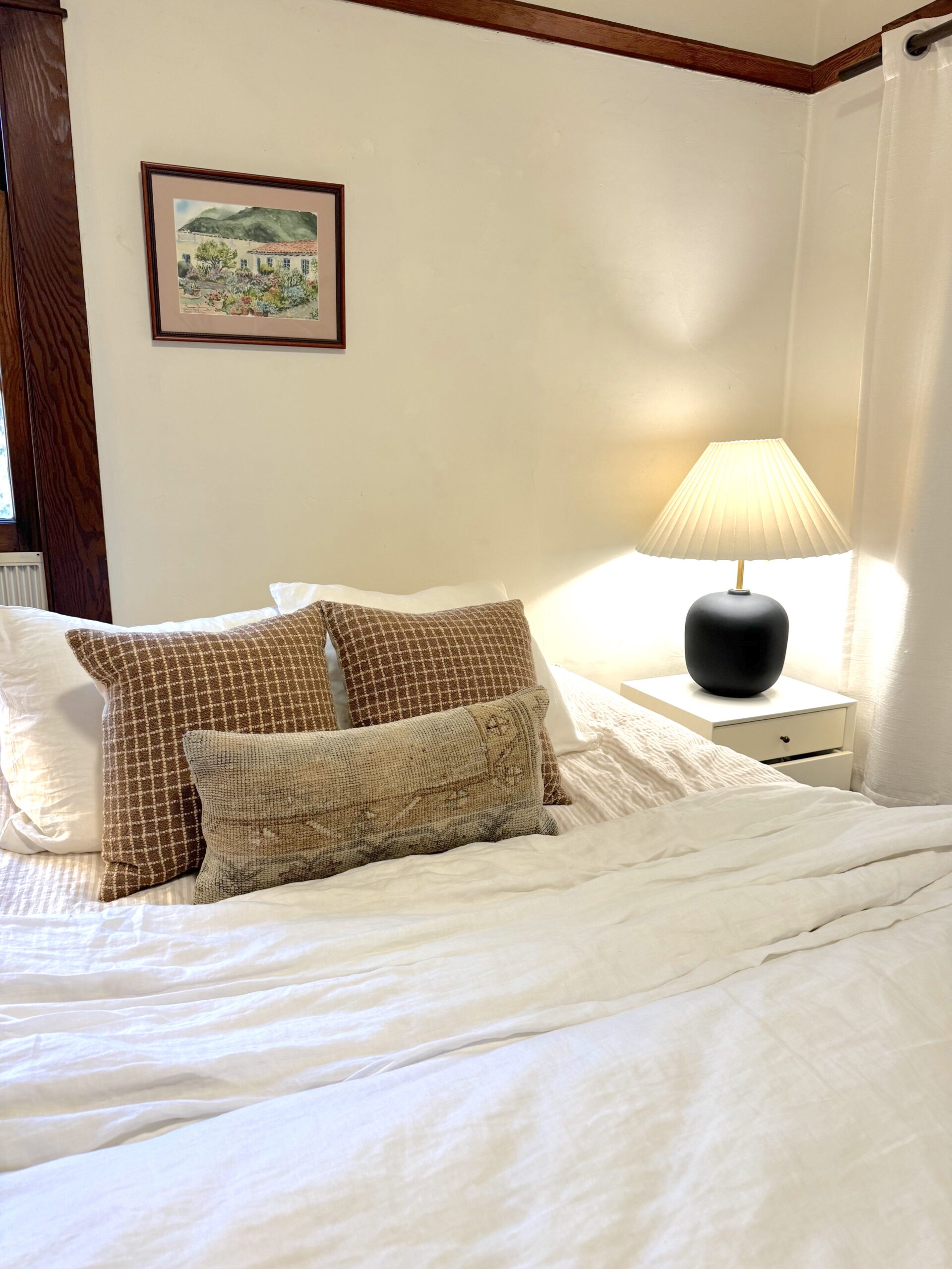 A bed made with fluffy white sheets and red pillows.