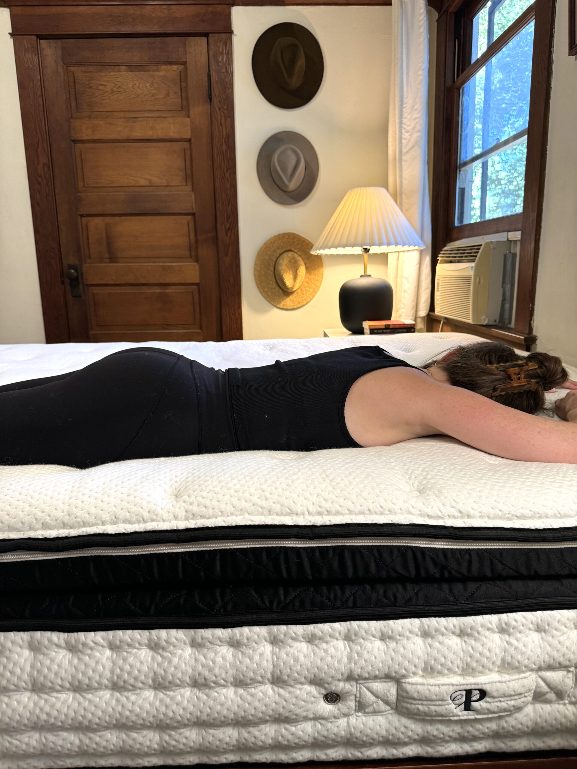 A women with her hair pulled back lies on top of a clean, white quilted mattress to demonstrate the support it offers.