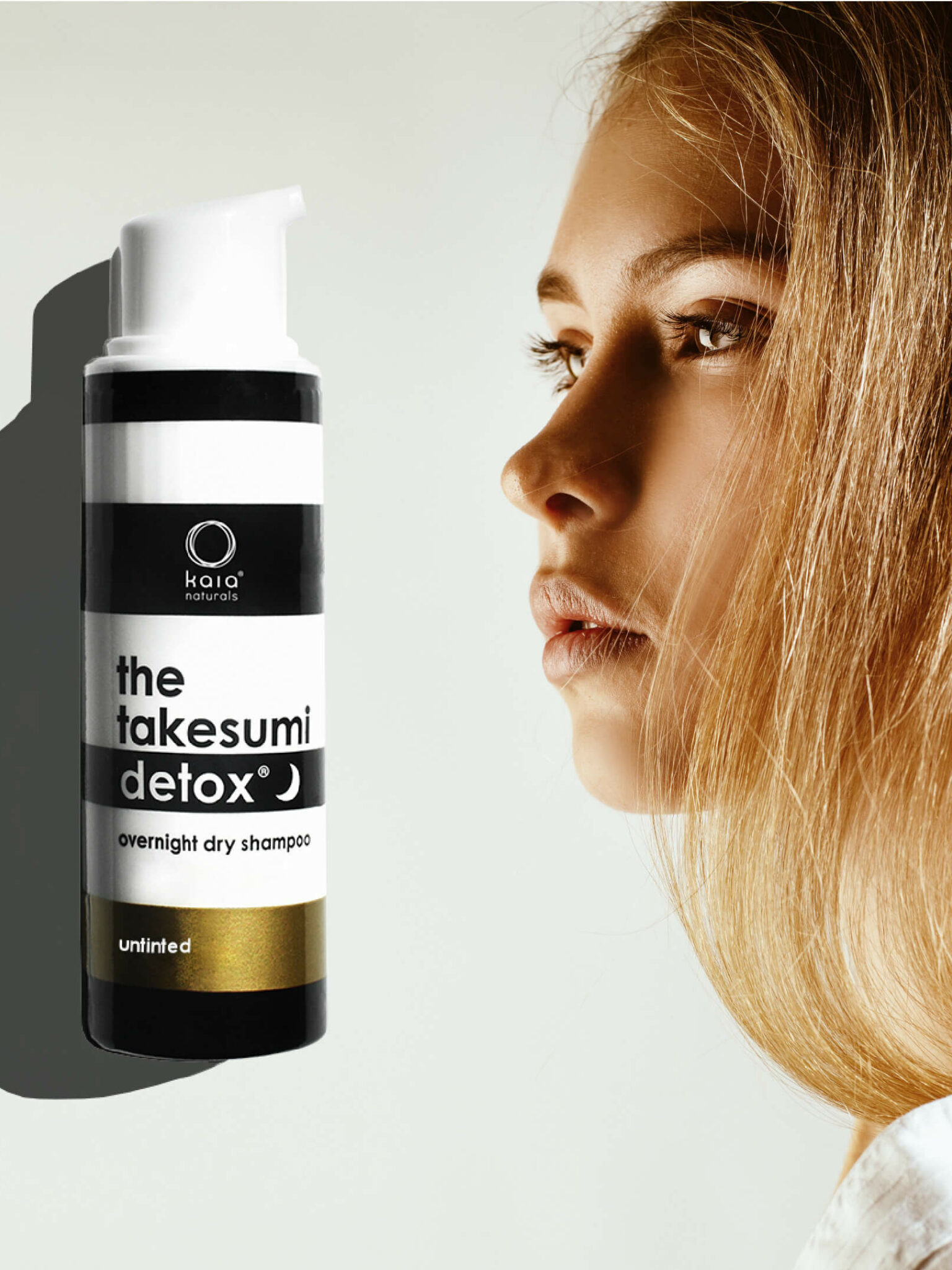 A bottle of "The Takesumi Detox Overnight Dry Shampoo - Untinted" is shown against a light background, next to the side profile of a woman with blonde hair.