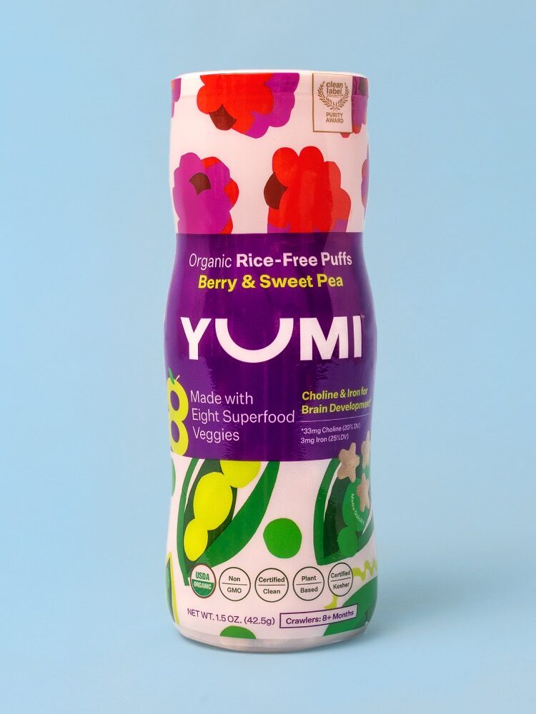 A container of Yumi Organic Rice-Free Puffs, Berry & Sweet Pea flavor, against a light blue background. The packaging highlights brain development nutrients and eight superfood veggies. Net weight: 11.5 oz.