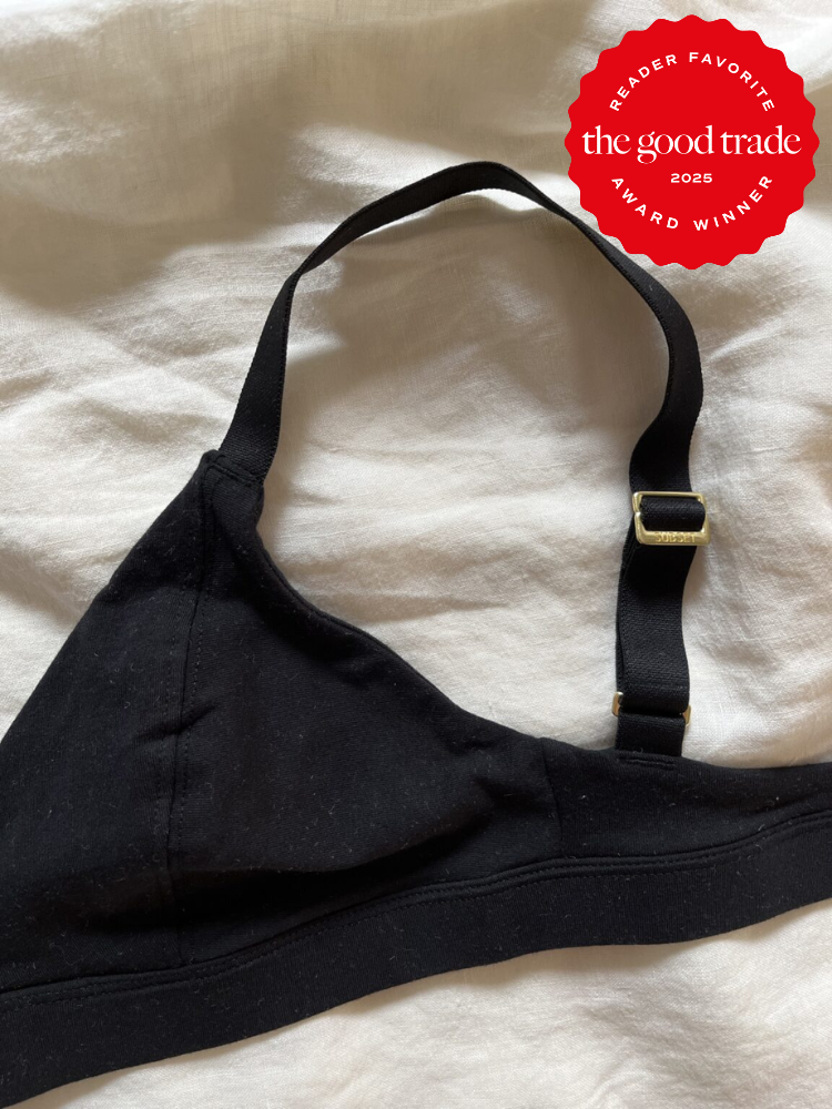 Black bra with adjustable strap on white fabric, featuring a red circular "Reader Favorite" award badge from "The Good Trade" for 2025 in the top right corner.