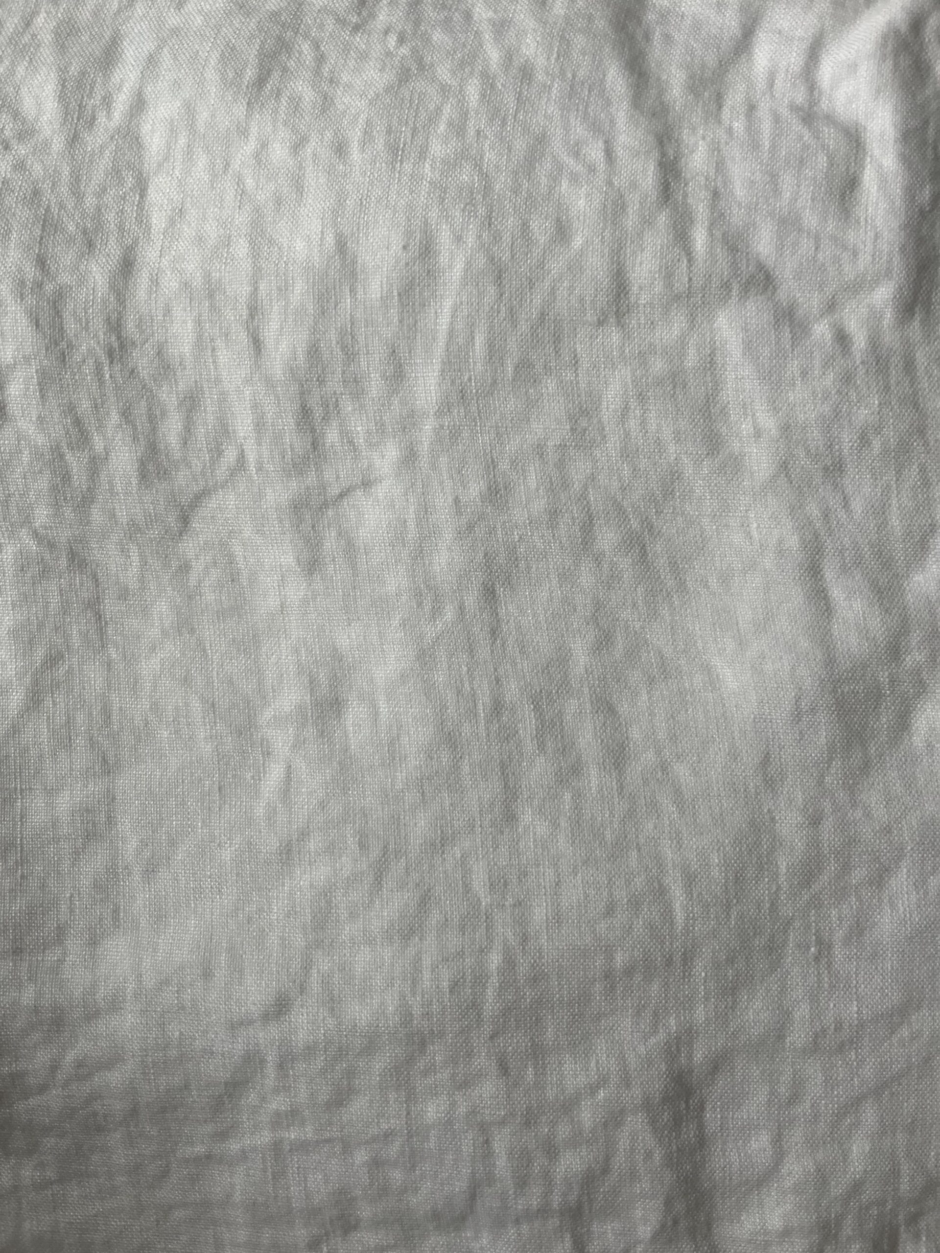 A close-up image of wrinkled, light gray fabric with visible texture and creases.